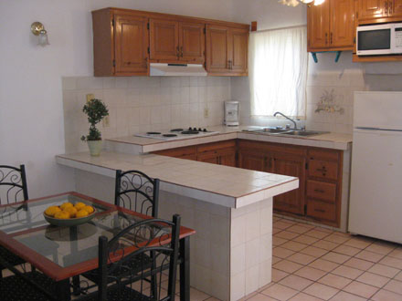 Fully-furnished kitchen
with tiled breakfast counter and adjacent dining area
with table and four chairs